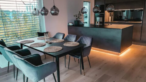 EWE Küche vom Küchenzentrum Steffl umgesetzt in Beton Schiefergrau, schwarze Kunststoffarbeitsplatte, Kücheninsel mit Beleuchtung, Spiegelrückwand