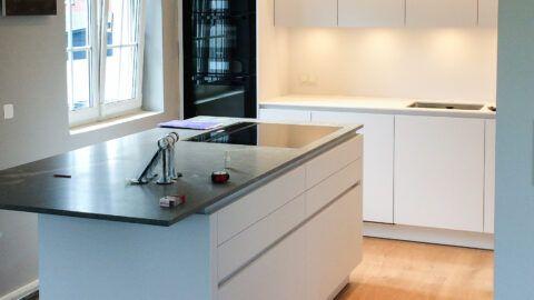 Küchenstudio Steffl Referenz ewe Küche grifflos weiß matt, Natursteinarbeitsplatte, Miele Geräte schwarz