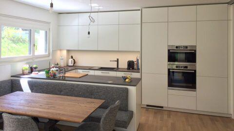 Designküche ewe grifflos kombiniert mit Griffen, offene Wohnsituation, dunkle Kunststoffarbeitsplatte, Franke Spüle und Armatur