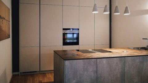 Referenzküche Marke LEICHT Betonlook kombiniert mit Mohair grifflos Keramikarbeitsplatte Rost